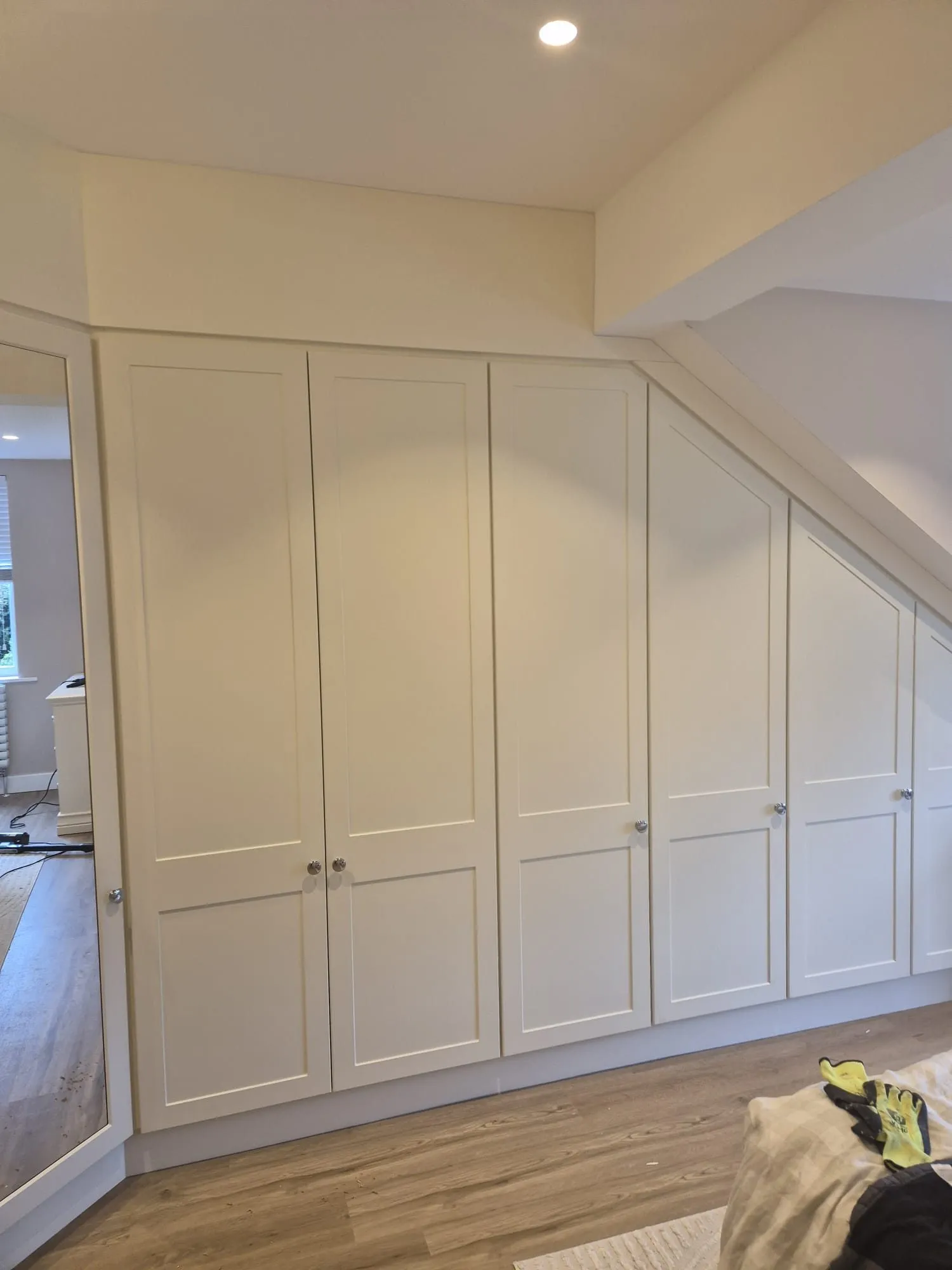 Long run of shaker fitted wardrobes turning into a mirrored corner unit