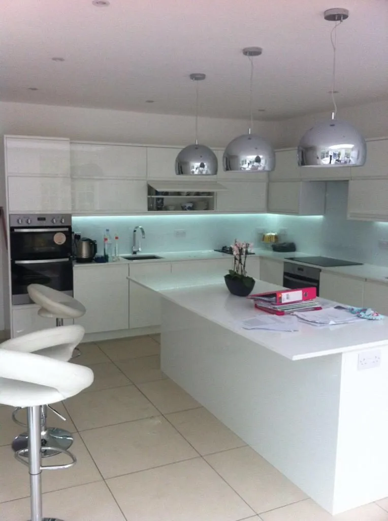 White gloss kitchen with island, chrome pendant lights and breakfast bar stools