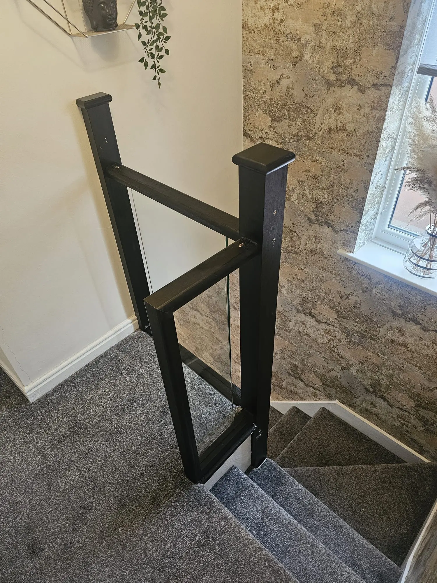 Finished staircase renovation with black newel posts, black handrail and glass balustrade