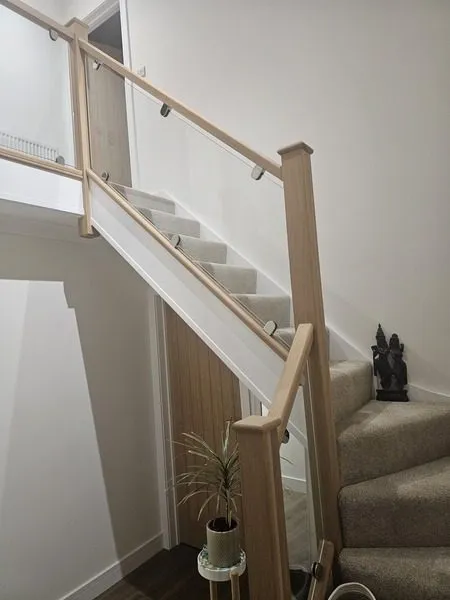 Half-landing turn of an oak staircase with frameless glass balustrade